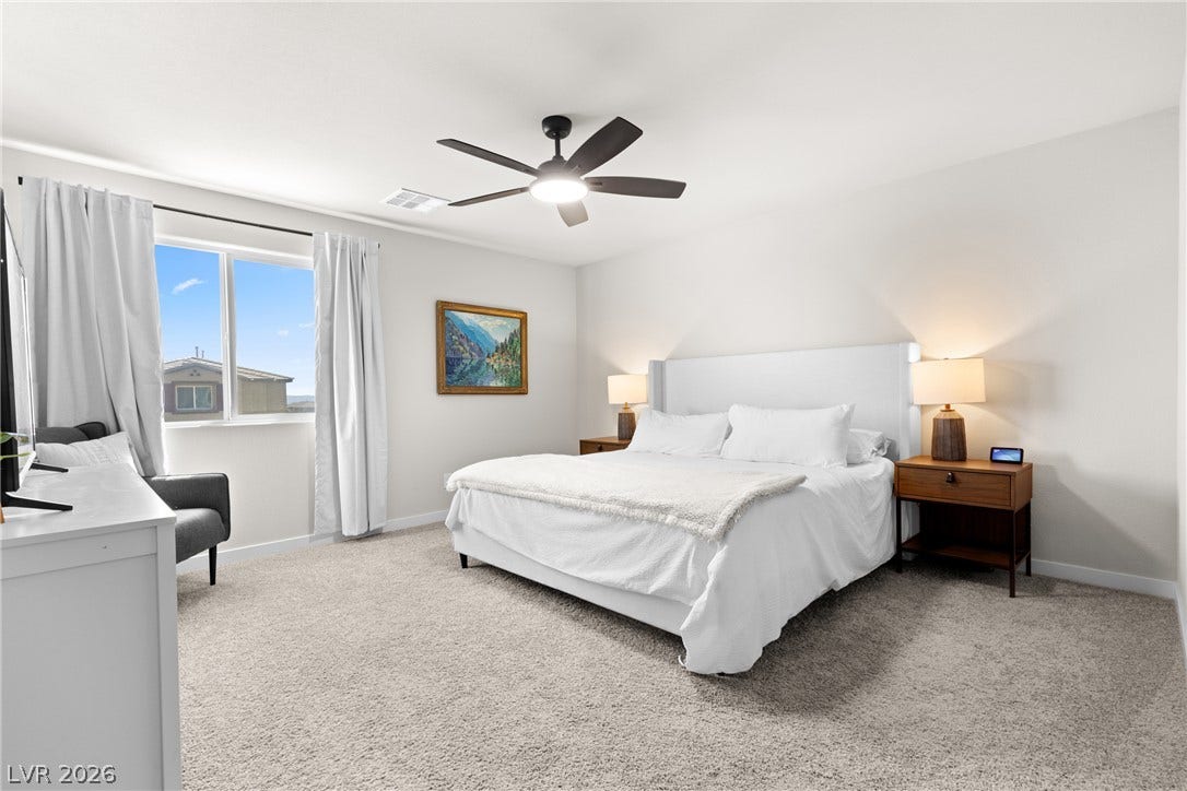 Plush carpet and a large window create a serene atmosphere in this bedroom.
