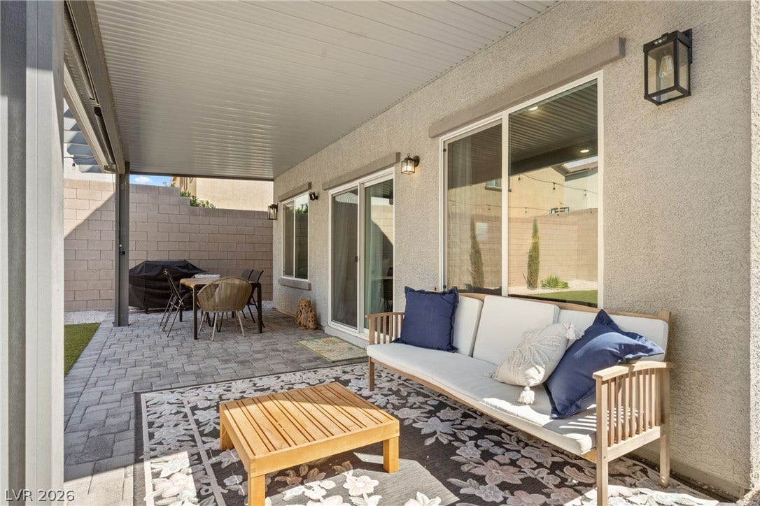 A spacious covered patio features clean stucco siding and paved brick flooring.