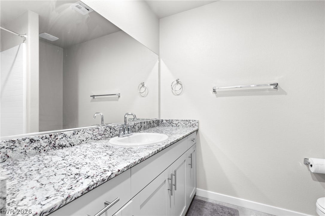 Polished stone countertops pair with clean cabinetry in a well-designed modern bathroom layout.