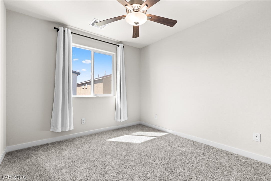 Plush carpeting and natural light define this cozy bedroom space.