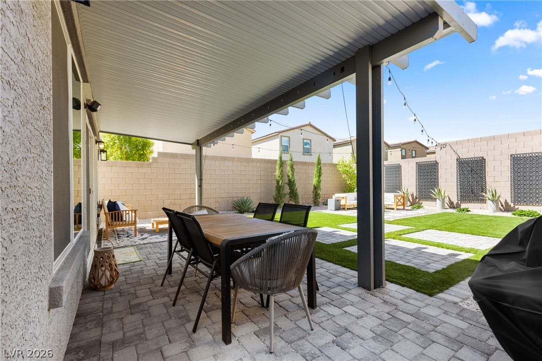 An inviting covered patio features modern pavers transitioning into a beautifully landscaped backyard.