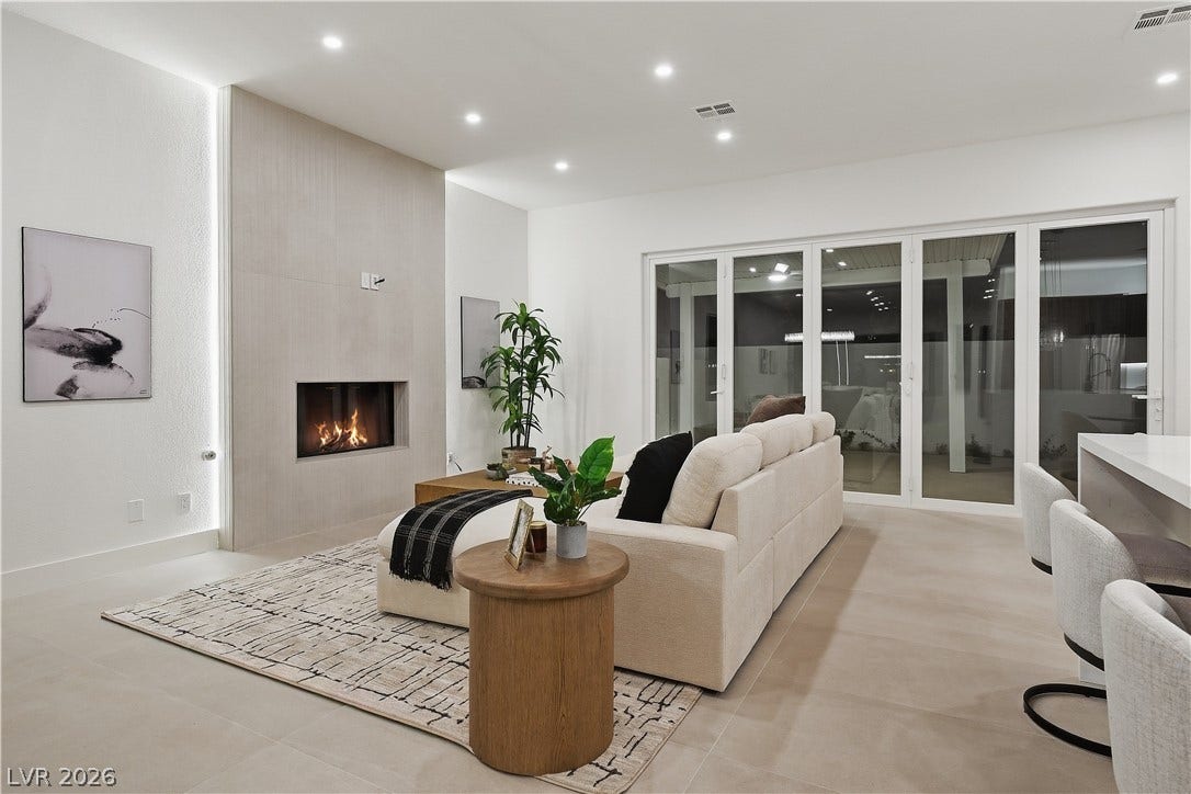 1612 Hidden Spring Drive, Las Vegas, NV 89117 Recessed lighting illuminates this modern living space featuring a sleek fireplace and sliding glass doors.