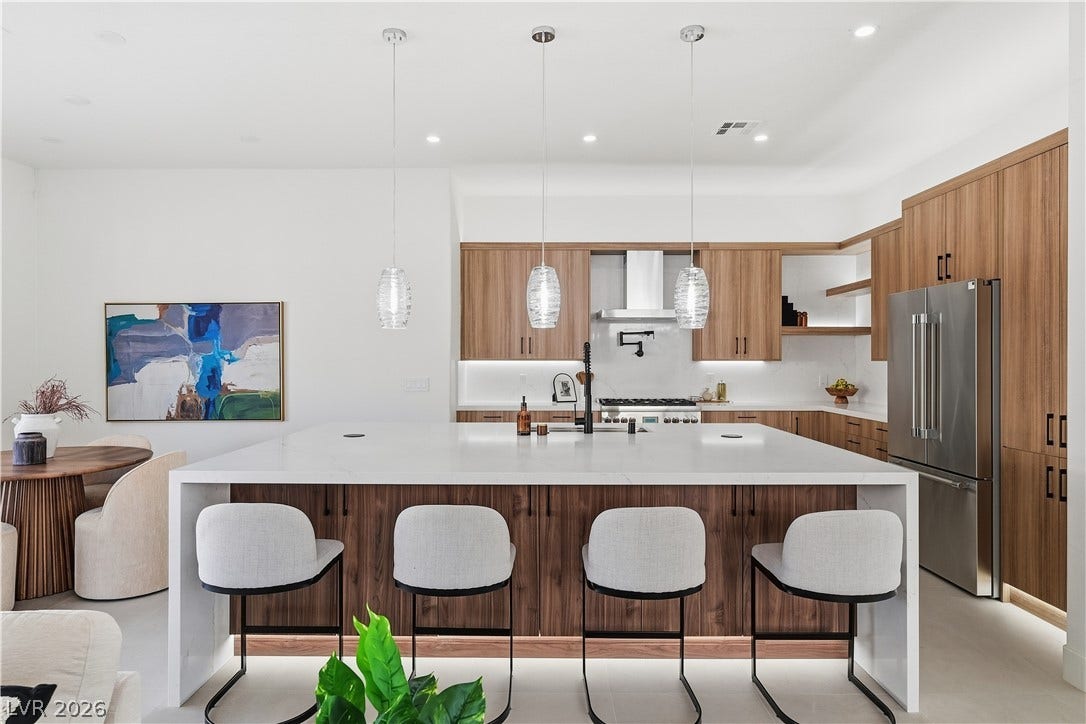 1612 Hidden Spring Drive, Las Vegas, NV 89117 Warm wood cabinetry and an expansive waterfall island create a modern culinary workspace.
