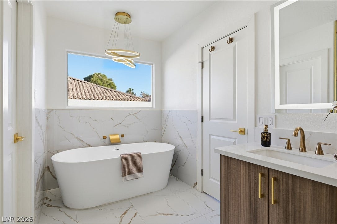 1612 Hidden Spring Drive, Las Vegas, NV 89117 Marble wall panels and a freestanding soaking tub anchor this refined bathroom space.