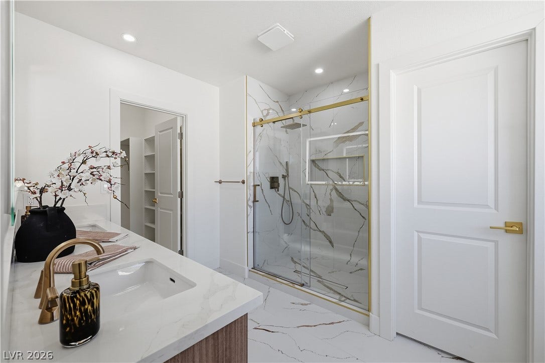 1612 Hidden Spring Drive, Las Vegas, NV 89117 Elegant stone finishes pair beautifully with gold fixtures in this modern bathroom.