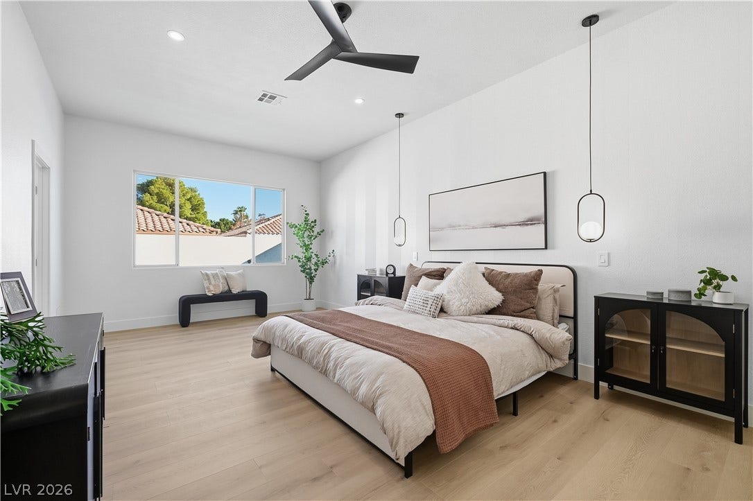 1612 Hidden Spring Drive, Las Vegas, NV 89117 Natural light pours through the large window of this airy bedroom with light wood flooring.