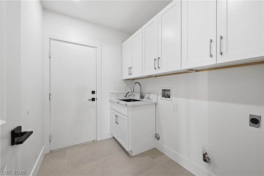 1612 Hidden Spring Drive, Las Vegas, NV 89117 Ample white cabinetry and a utility sink highlight this functional laundry space with tile flooring.