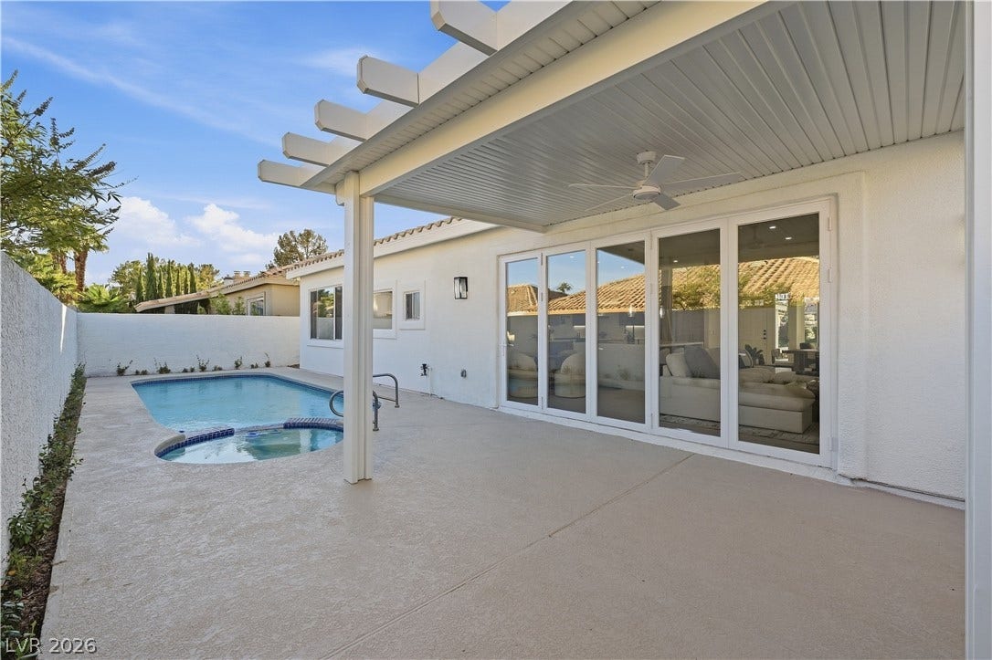 1612 Hidden Spring Drive, Las Vegas, NV 89117 An inviting backyard patio overlooks a sparkling pool and spa set against a stucco exterior.