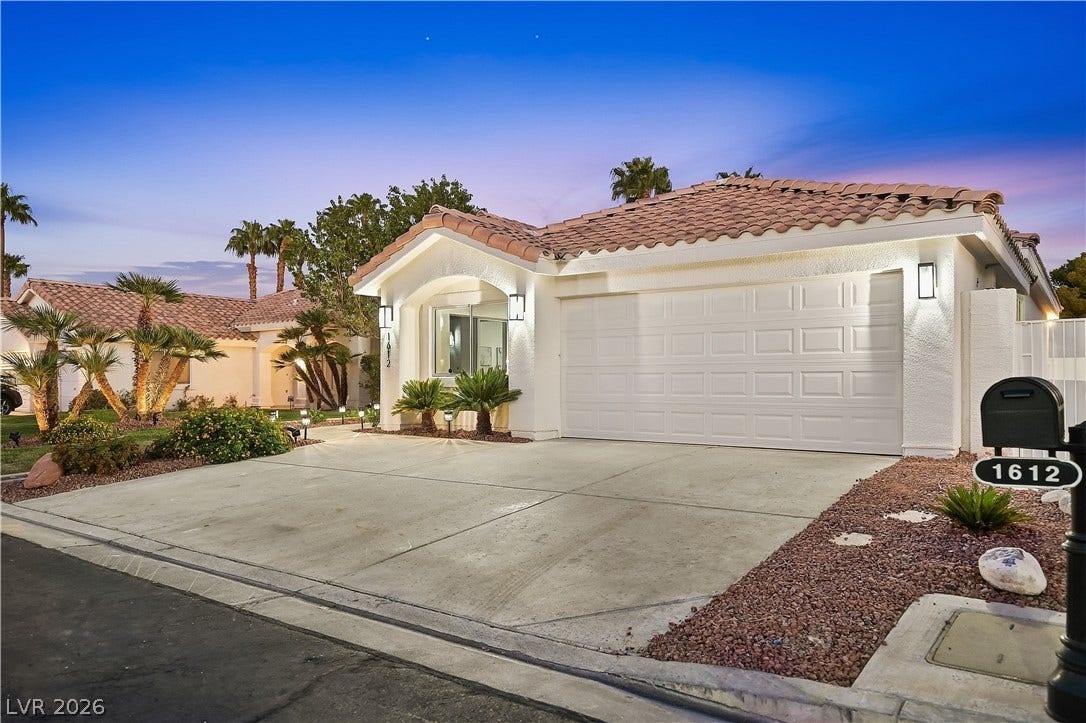 1612 Hidden Spring Drive, Las Vegas, NV 89117 Mediterranean architectural details and a spacious driveway define this desert landscaped exterior.