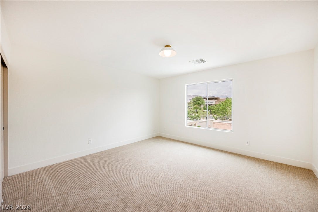 A single window illuminates a clean space lined with textured carpeting.