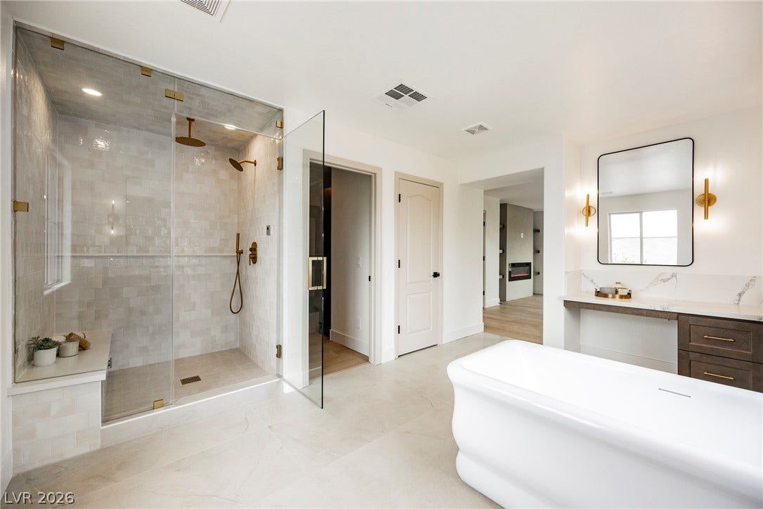 An elegant soaking tub highlights this bathroom with its spacious, glass-enclosed walk-in shower.