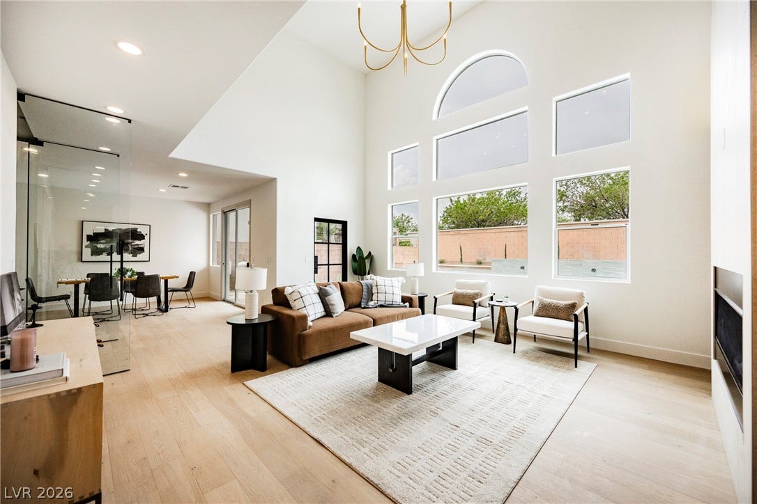 Towering windows and soaring vaulted ceilings define this airy living space with light hardwood floors.
