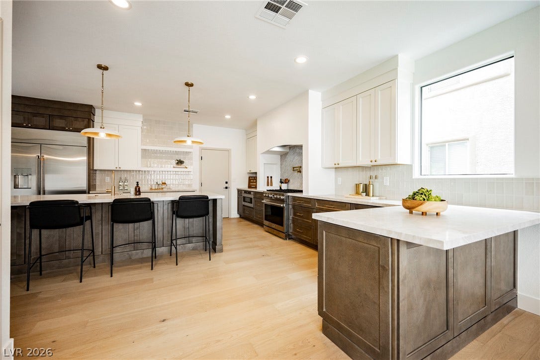 Gleaming wood floors and dual islands define this exceptionally airy, light-filled kitchen space.