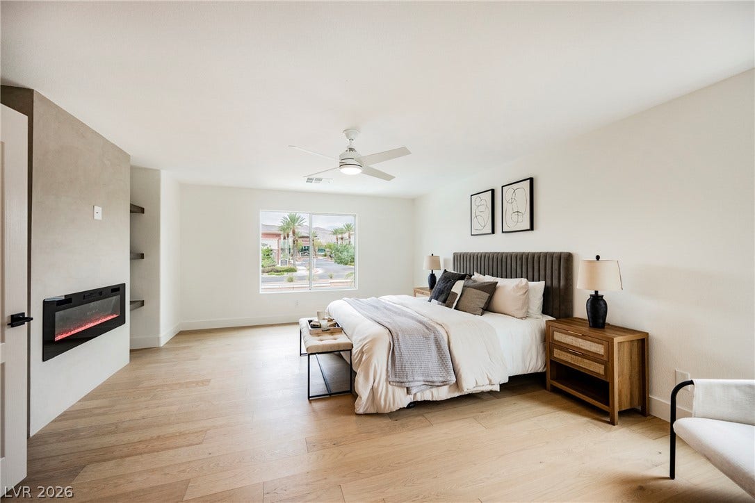 Warm wood flooring and a modern fireplace anchor this peaceful primary bedroom retreat.