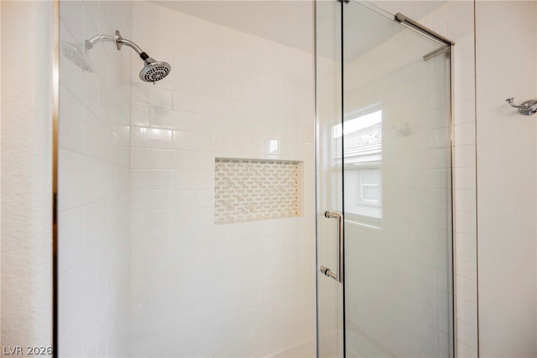 Crisp subway tile surrounds this modern shower featuring a built-in niche and glass enclosure.