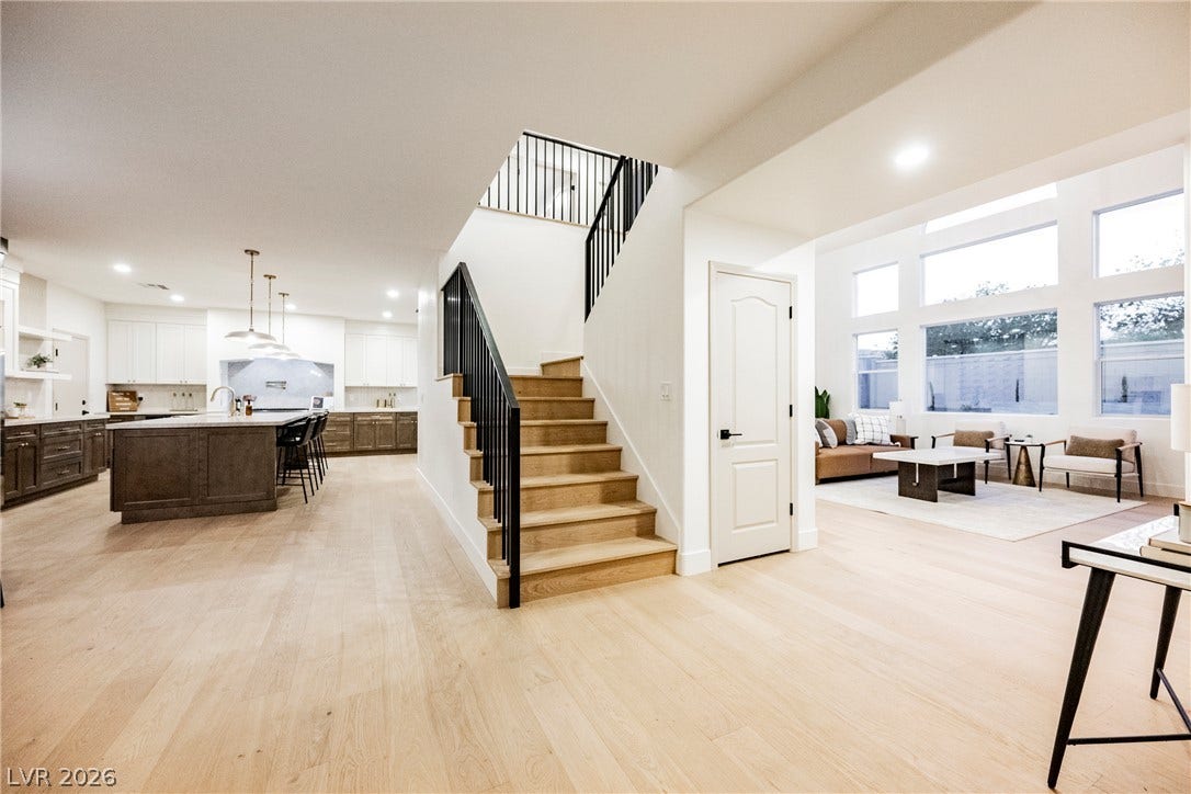 An open floorplan seamlessly connects the airy living spaces anchored by a central wood staircase.