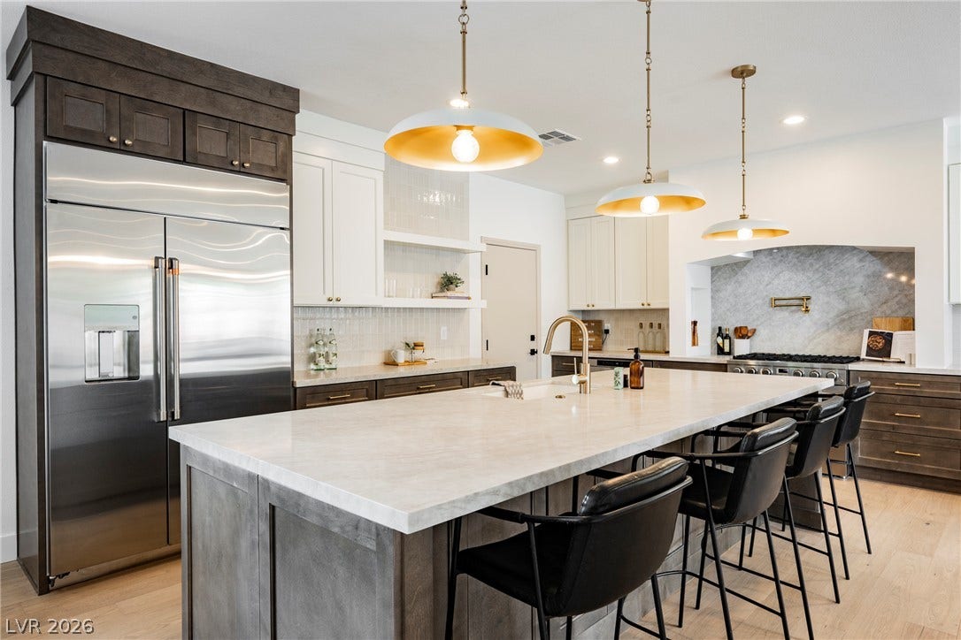 Gleaming stone countertops and a spacious island anchor this light-filled culinary workspace.