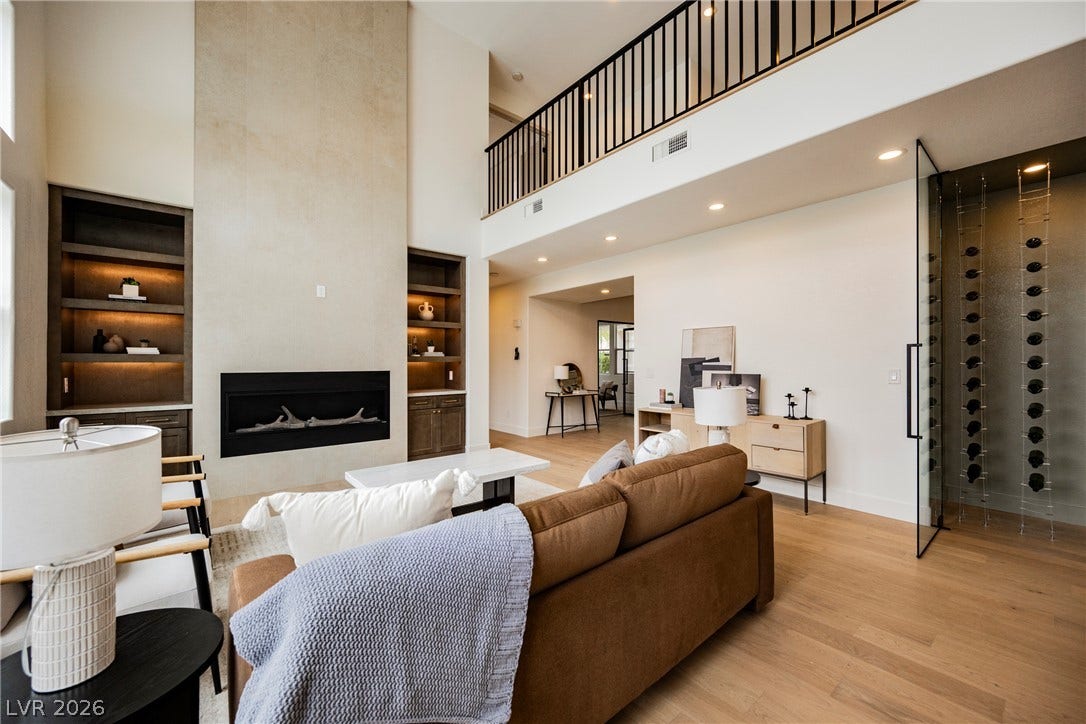 Double-height ceilings and a sleek linear fireplace anchor this open-concept living space.