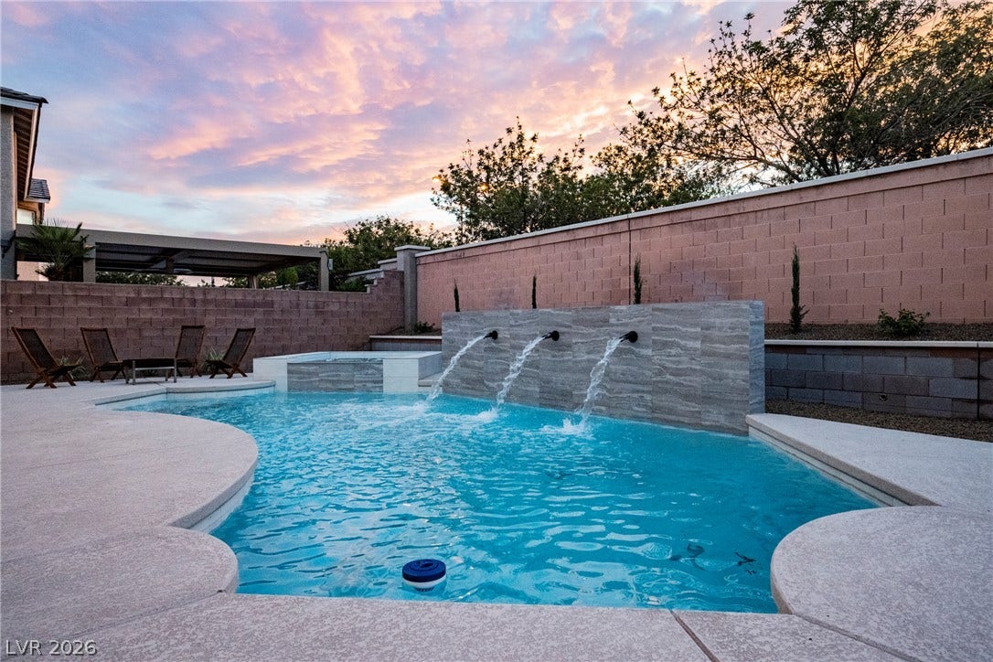 An inviting backyard oasis features a swimming pool accented by three elegant water fountains.