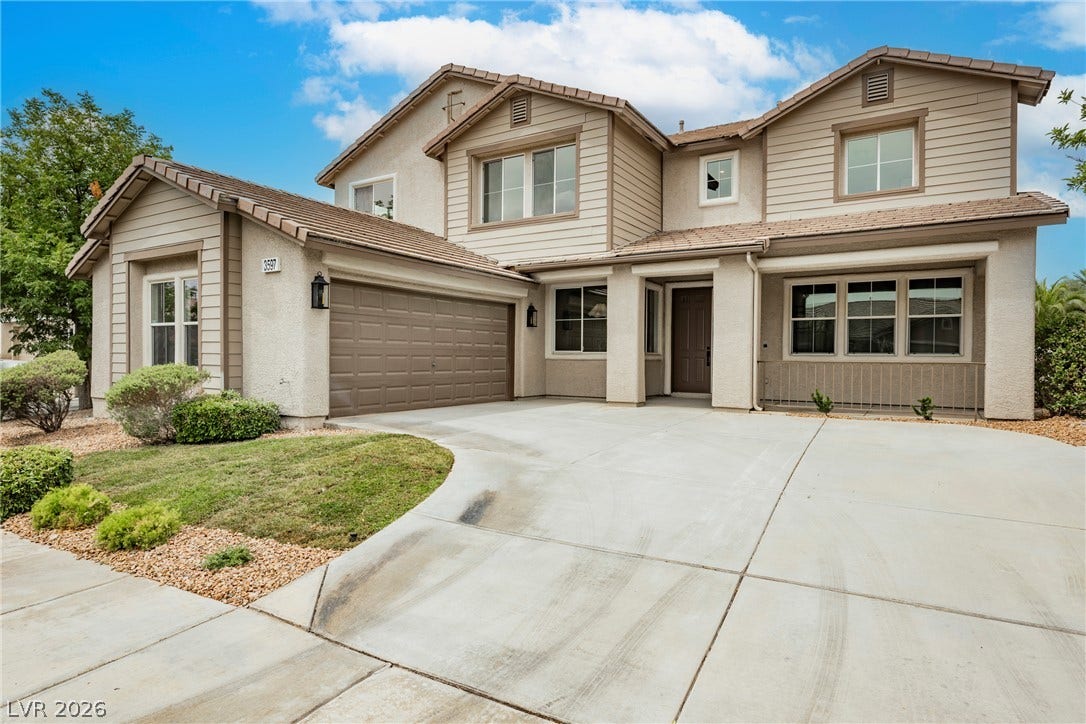 An expansive concrete driveway leads to a classic two-story exterior with mixed siding finishes.