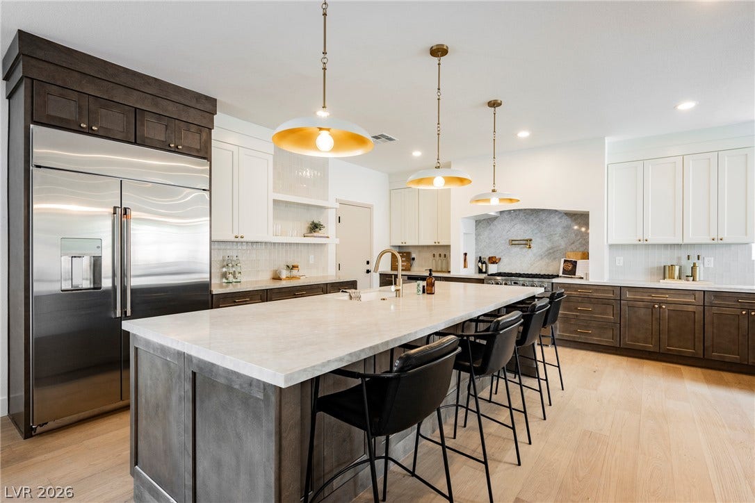 An expansive kitchen island anchors this modern culinary space featuring premium stone countertops and hardwood flooring.