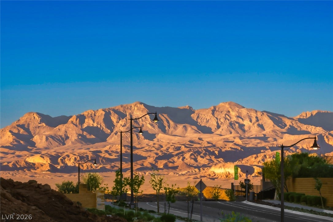 30 Sand Star Lane, Henderson, NV 89011 Dramatic mountain peaks rise majestically beyond the neighborhood street as dusk begins to settle.