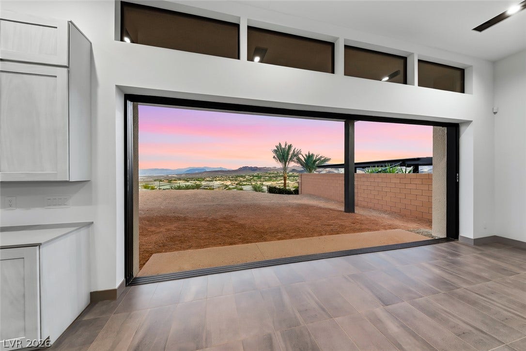 30 Sand Star Lane, Henderson, NV 89011 Massive sliding glass doors reveal a panoramic desert sunset and mountains from the living space.