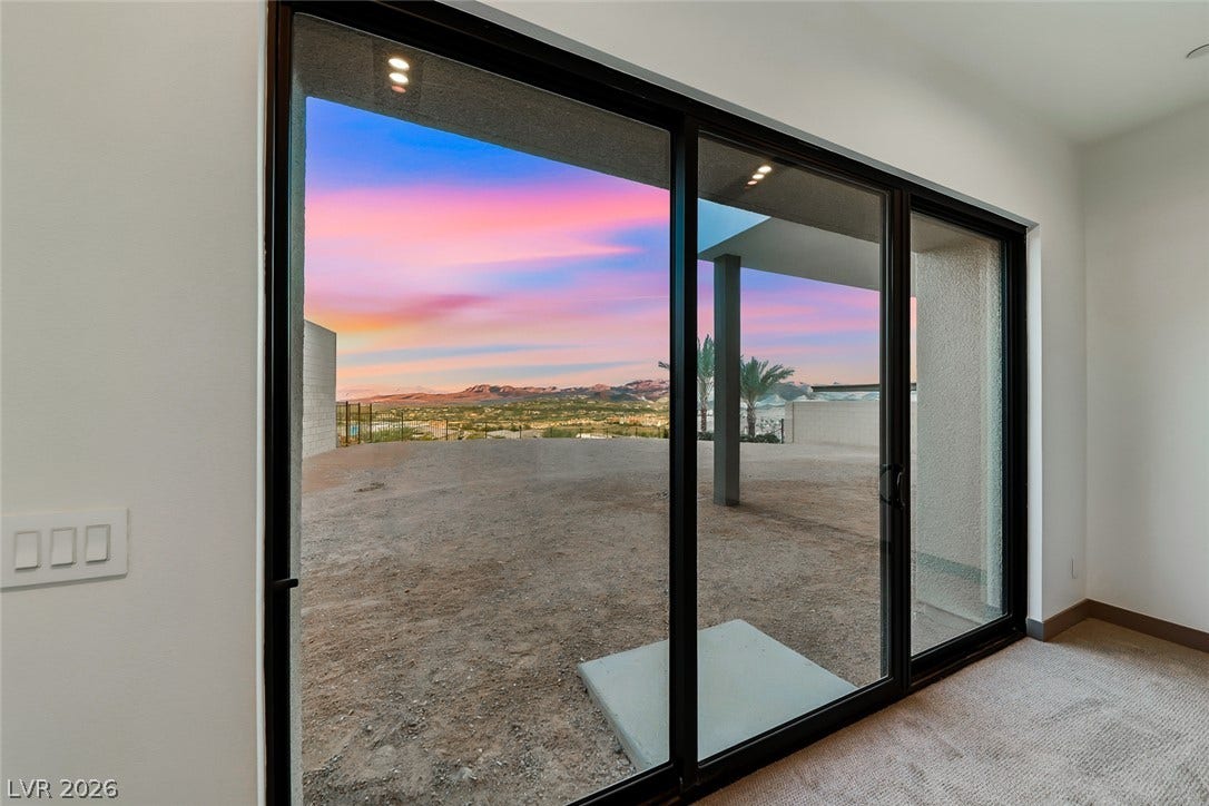 30 Sand Star Lane, Henderson, NV 89011 Massive sliding glass doors reveal panoramic mountain views against a vivid twilight sky.