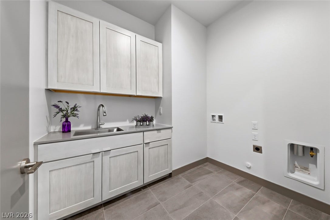 30 Sand Star Lane, Henderson, NV 89011 A dedicated utility space with shaker cabinetry, a sink, and stone countertops over tile flooring.