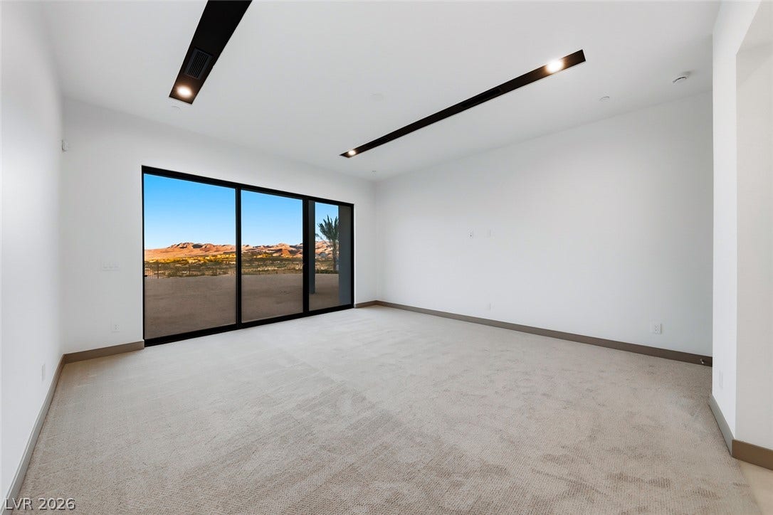 30 Sand Star Lane, Henderson, NV 89011 Sliding glass doors frame expansive desert mountain views from this carpeted bedroom.