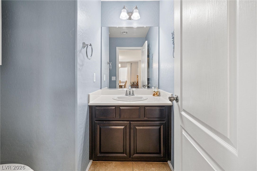 8944 Red Tapestry Court, Las Vegas, NV 89149 Clean lines and a dark wood vanity anchor this cozy powder room.