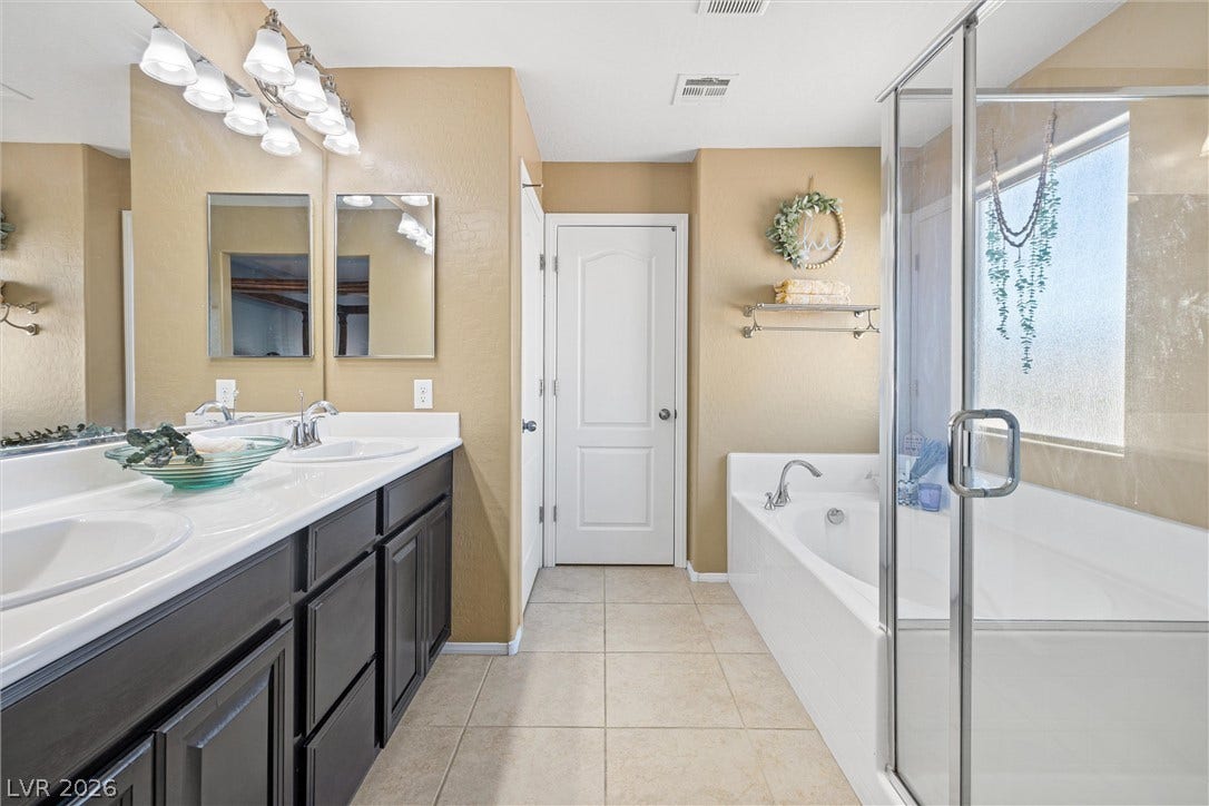8944 Red Tapestry Court, Las Vegas, NV 89149 A spacious layout features a dual vanity alongside a separate soaking tub and glass shower and walk in closet.