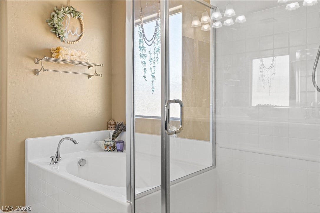 8944 Red Tapestry Court, Las Vegas, NV 89149 A glass-enclosed shower stands adjacent to a built-in soaking tub with classic tile surrounds.