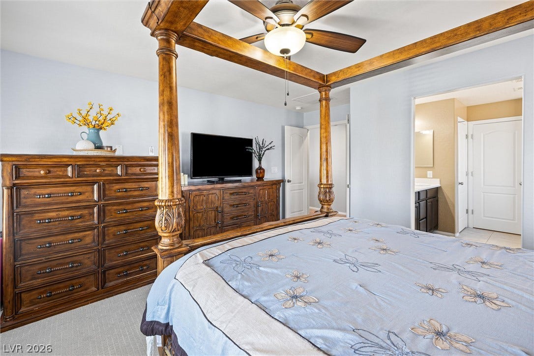 8944 Red Tapestry Court, Las Vegas, NV 89149 A spacious primary bedroom features soft neutral walls, light-colored carpeting, and access to an adjacent bathroom.