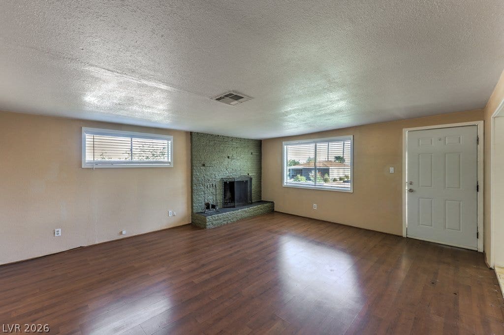 580 Karen Way, Henderson, NV 89015 Rich wood-textured flooring flows toward a brick wood-burning fireplace in this open living space.