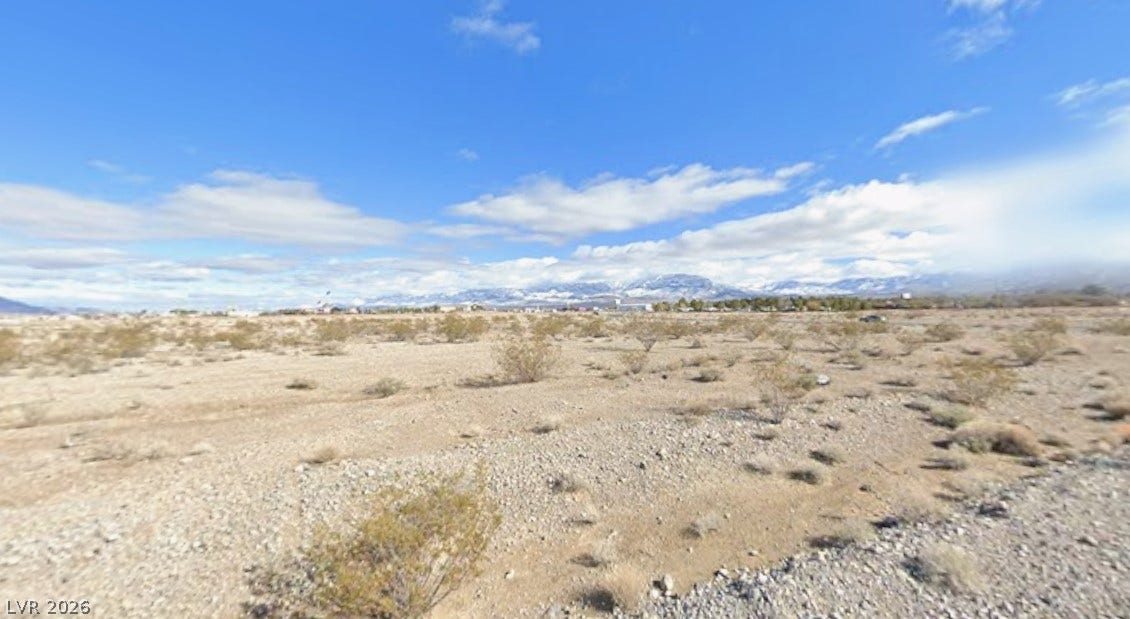 Vast desert terrain stretches toward snow-capped mountain peaks under a clear blue sky.