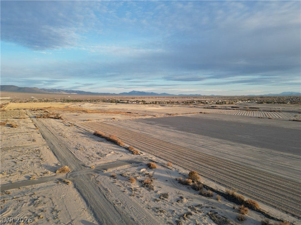 Vast desert acreage unfolds beneath wide skies and distant mountain silhouettes.