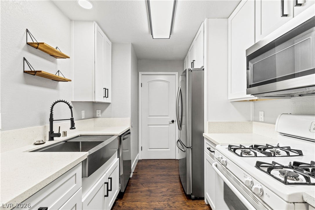 Gleaming stone countertops and stainless steel appliances complete this updated gallery kitchen layout.