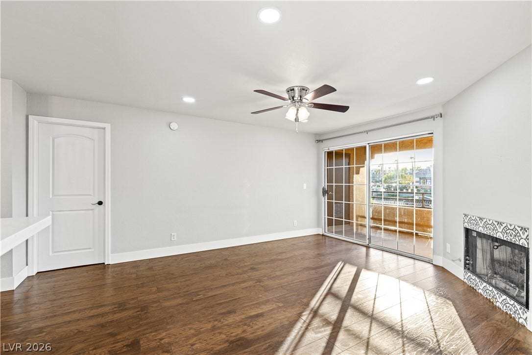 Rich wood flooring and a modern fireplace anchor this light-filled room opening to a balcony.