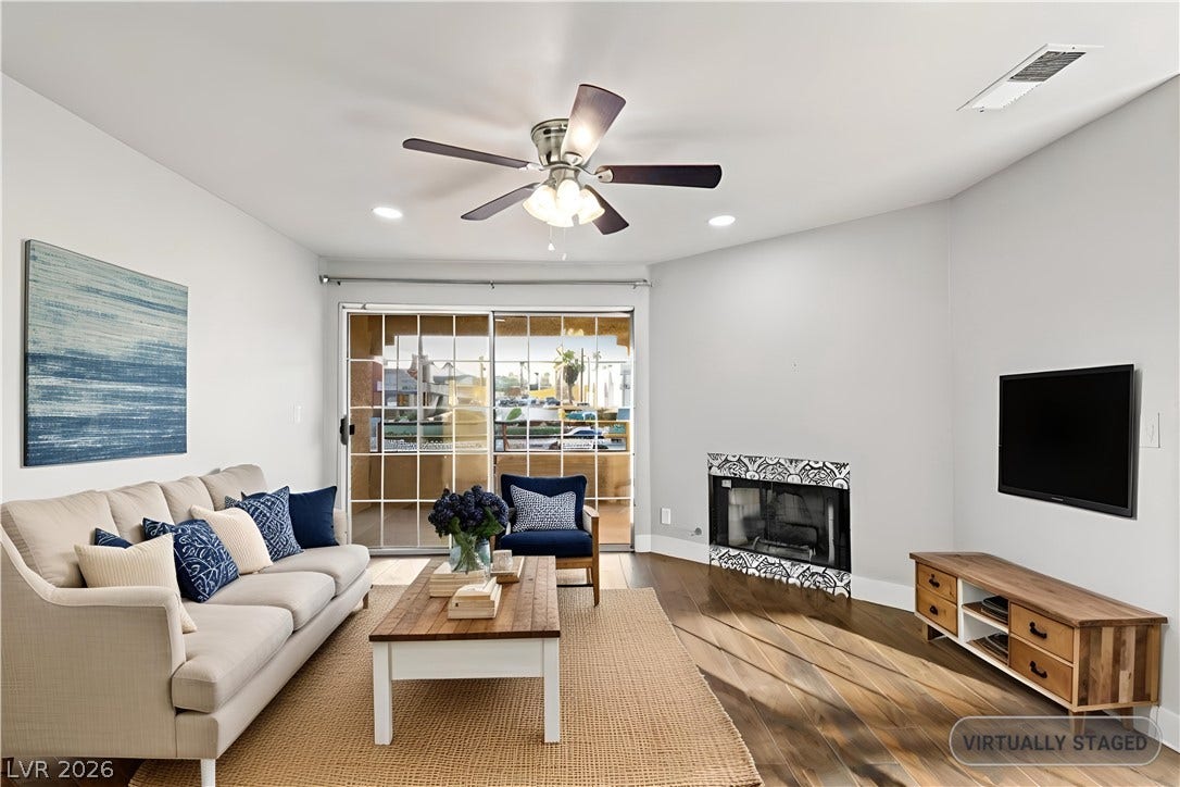 Rich hardwood flooring complements the corner fireplace and sliding glass door in this inviting room.