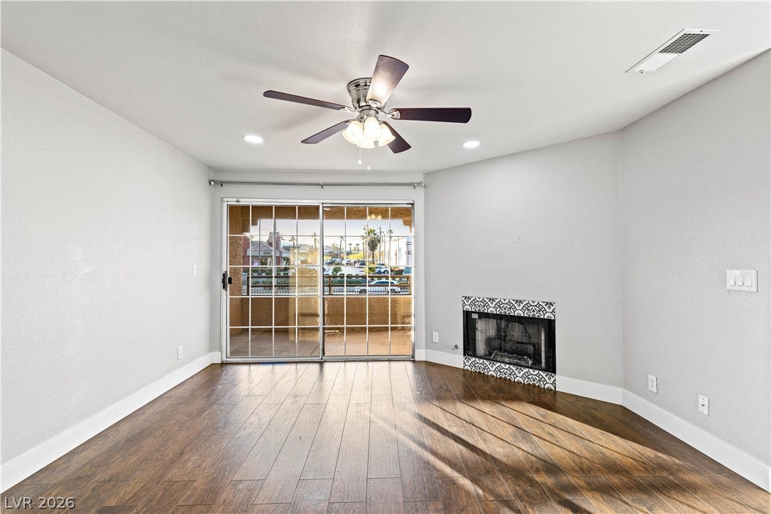 Rich wood-look flooring and a tiled corner fireplace anchor this inviting living space.