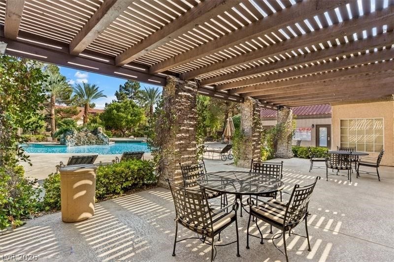 An expansive wood pergola shades a concrete patio overlooking a resort-style swimming pool.