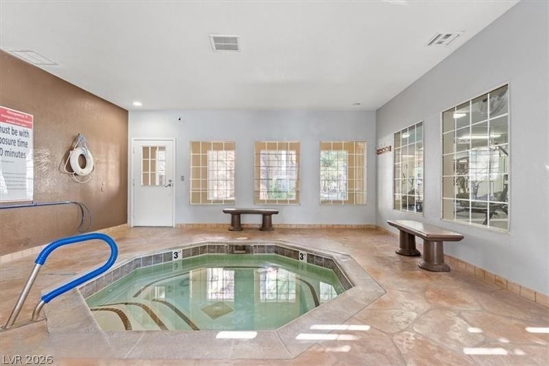 An inviting indoor spa area features textured stone tile flooring and large viewing windows.