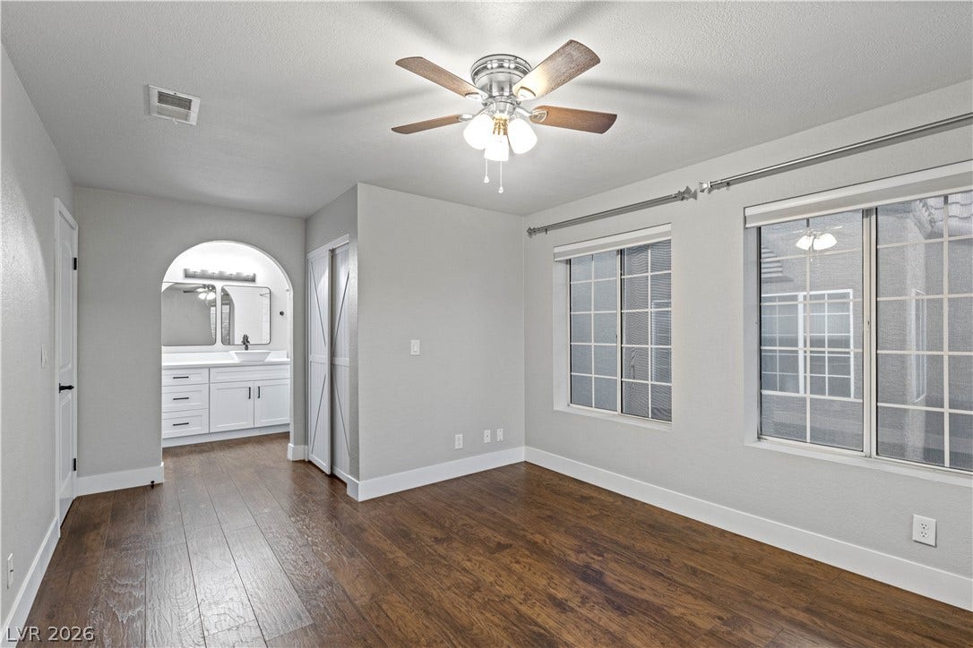 Rich hardwood floors and elegant arched doorways anchor this inviting, light-filled primary suite.