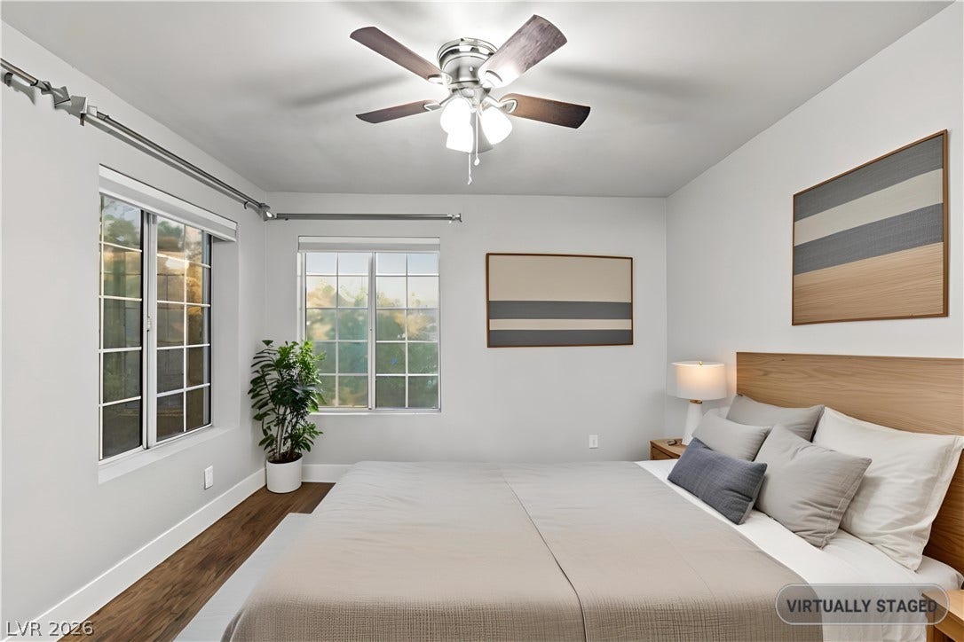Multi-pane windows fill this quiet bedroom with natural light across rich hardwood floors.