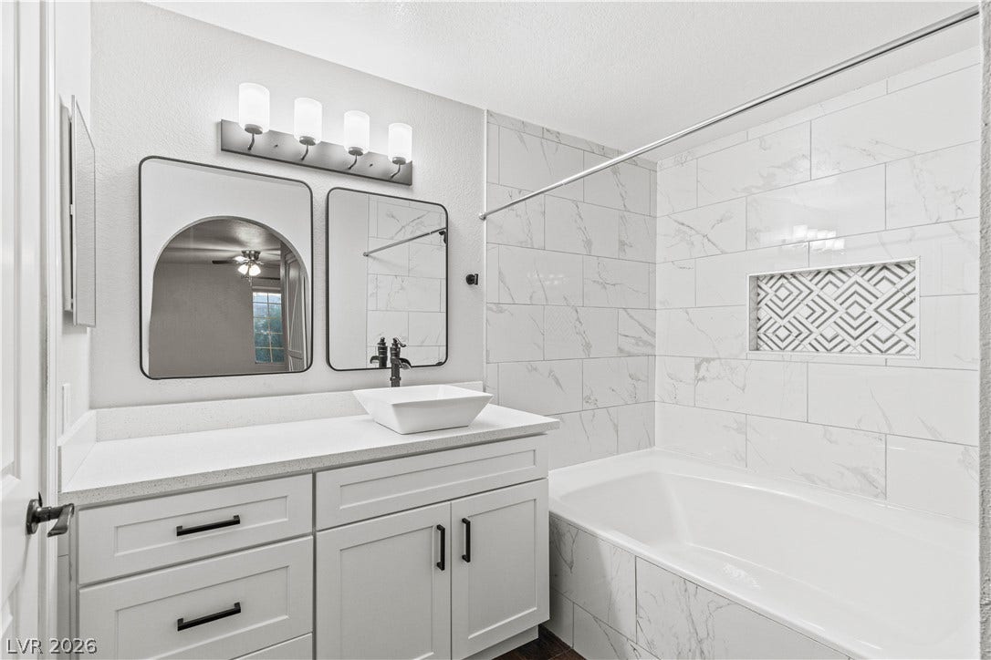 Clean modern finishes define this sleek bathroom featuring a deep tub and tiled shower surround.