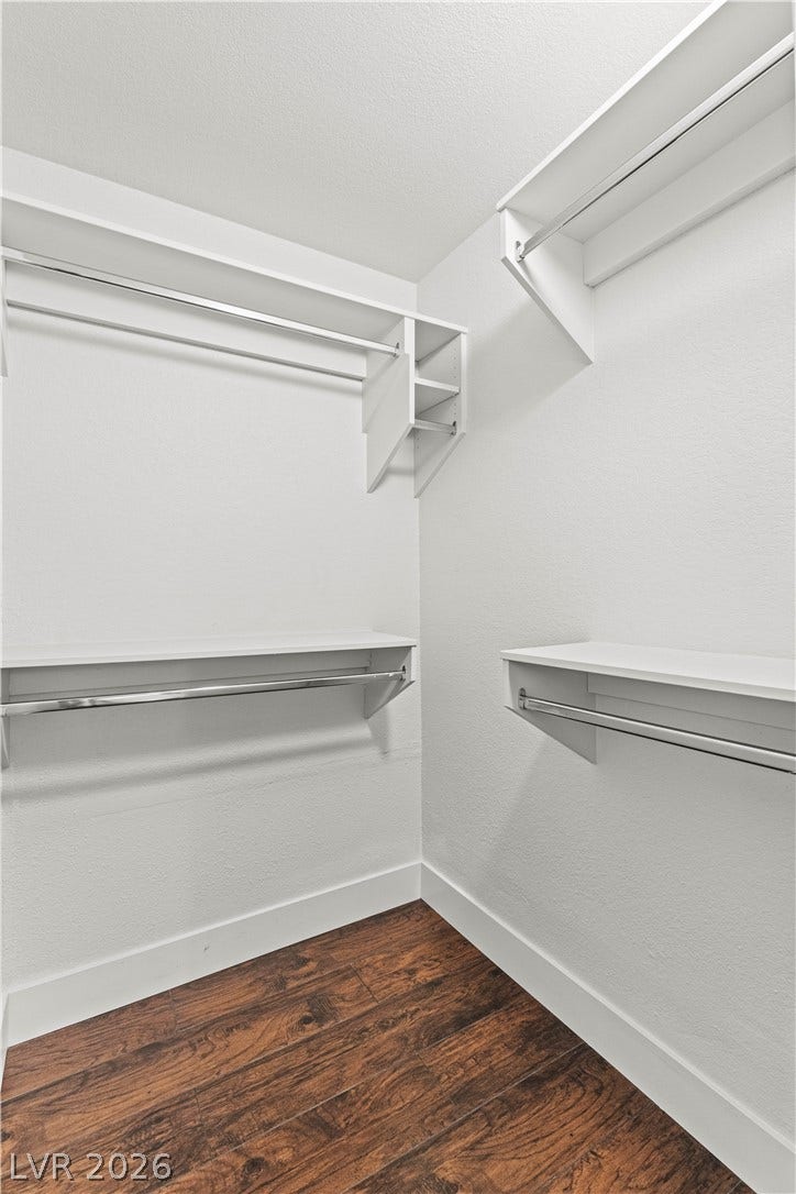 Rich wood flooring complements built-in shelving inside this organized wardrobe space.