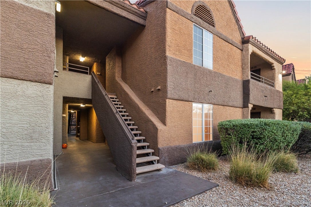 Stucco exterior finishes and concrete stairs define the entrance of this multi-level residential building.