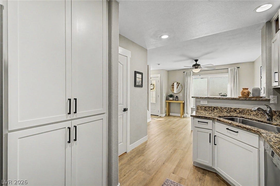 199 Winnsboro Street, Henderson, NV 89074 Gleaming stone countertops and classic cabinetry elevate this bright kitchen leading to the entryway.
