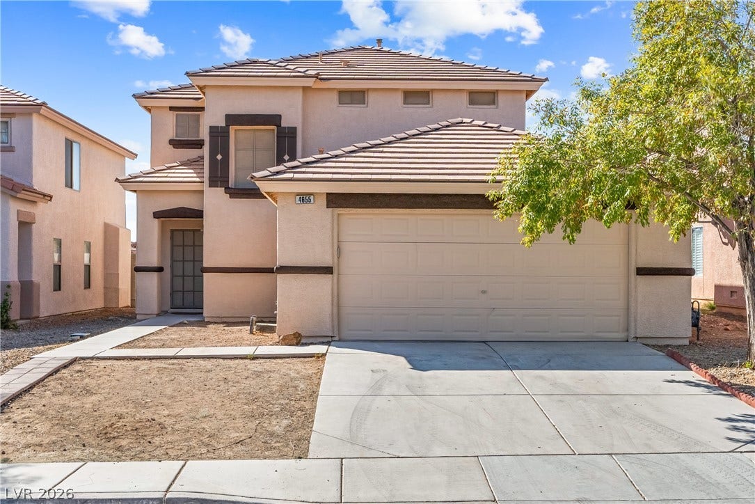 A classic two-story stucco exterior stands behind a concrete driveway and tidy desert landscaping.